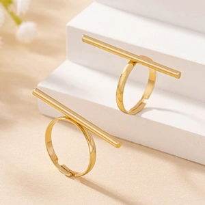 Macro detail of golden minimalist open rings with geometric T-bar design on white stairs