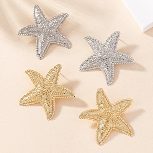Macro detail of starfish earrings with textured metallic finish in gold and silver