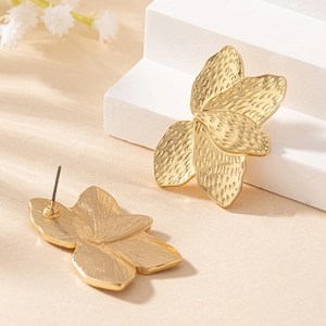Elegant gold flower earrings with hammered texture petals on white display pedestal