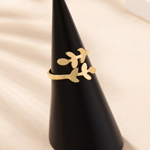 Fashionable gold leaf shaped open ring with textured metal branches on a display stand