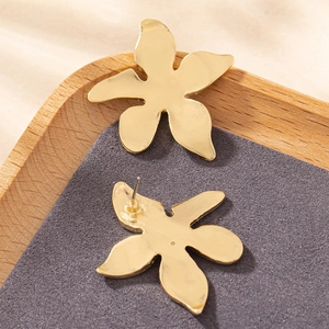 Elegant gold flower stud earrings in a five-petal design on a grey velvet tray