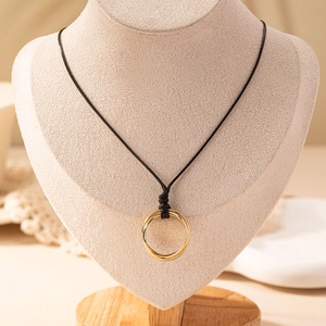Detail of minimalist gold double-ring pendant on black woven cord over a textured bust