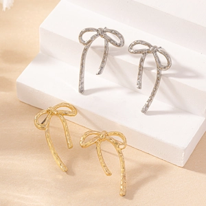 Elegant gold and silver bow drop earrings with hammered texture on white display