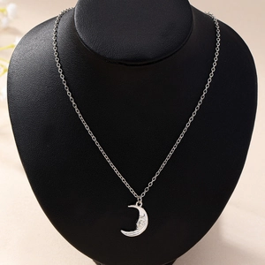 Silver crescent moon face pendant necklace displayed on a black neck mannequin