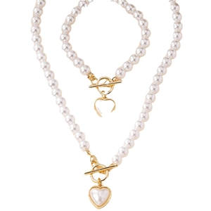 Parure de bijoux en perles avec pendentifs cœur et fermoirs à bascule dorés sur fond blanc