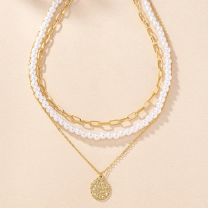 Gros plan d'un collier doré à trois rangs avec maillons épais, perles et pendentif pièce