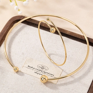 Ensemble collier ras du cou à boules dorées et bracelet ouvert sur plateau bois