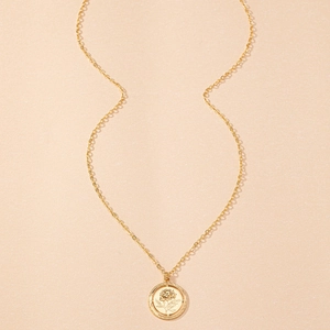 Close-up of golden coin pendant necklace featuring an intricate rose flower relief