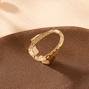 Minimalist wide hollow oval hammered gold ring with textured metallic finish on brown display