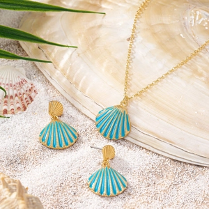 Golden shell necklace and earring set with blue enamel on white sand and palm leaf