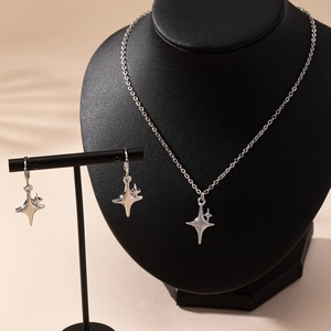 Elegant silver four-point star necklace and earrings jewelry set on display
