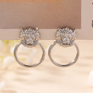 Close-up of silver lion head door knocker earrings with detailed metal texture