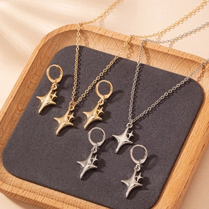 Elegant gold and silver four-pointed star pendant necklace and earring jewelry set on a tray
