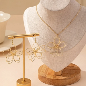 Parure de bijoux fleurs dorées avec collier et boucles d'oreilles ajourés sur présentoir