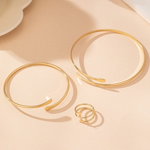Gros plan détaillé sur l'ensemble de bracelets dorés et la bague spirale à trois couches