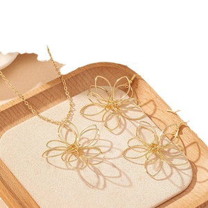 Ensemble collier et boucles d'oreilles fleurs en fil doré sur un plateau en velours