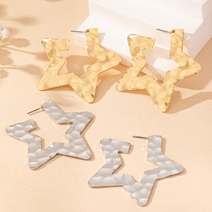 Detail of hammered metal star earrings in gold and silver finish with textured surface