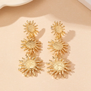 Close-up of golden triple sunflower drop earrings featuring a hammered metal texture