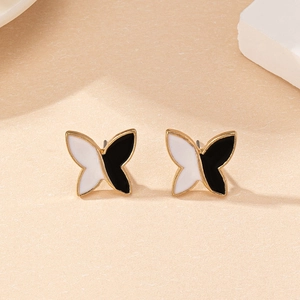 Close-up of butterfly stud earrings with gold edges and black and white enamel fill