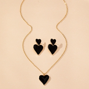 Détail de l'ensemble de bijoux dorés avec collier et boucles d'oreilles cœur noir