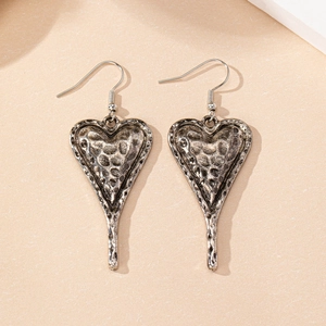 Detail of vintage heart drop earrings with hammered silver finish and long pendant style