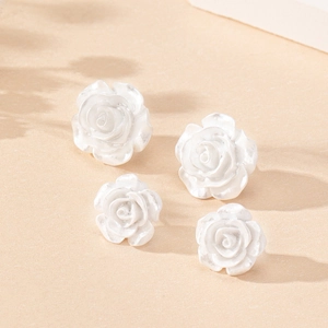 Macro shot of pearl white rose earrings in resin with layered petals and soft pearly luster