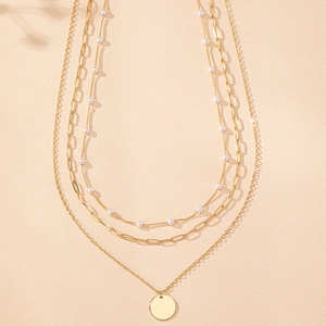 Detailed view of triple-layered gold necklace with pearls and circular pendant