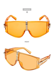 Detail view of orange oversized sunglasses with silver metal bridge and hinges