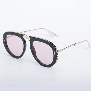Black folding sunglasses with rhinestone trim and pink gradient lenses in gold frame