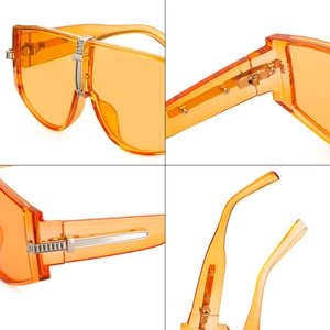 Orange oversized sunglasses with translucent frame and metal hinge detail view