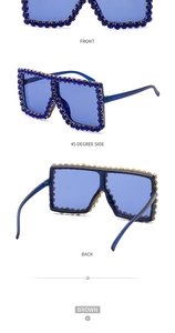 Macro view of oversized square sunglasses featuring blue rhinestones and translucent frames