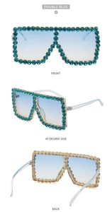 Detail view of oversized sunglasses with blue rhinestones and gradient lenses
