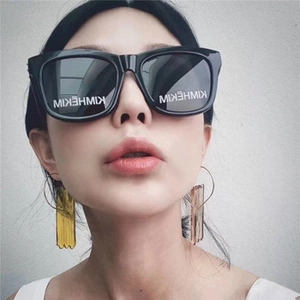 Detail of square polarized sunglasses featuring branded lenses and acrylic drop earrings