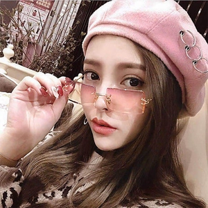 Close-up of pink gradient rimless sunglasses and beret with metal rings decoration