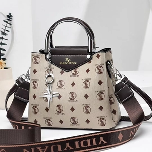 Close-up of the beige handbag with letter prints, silver handle, and star pendant