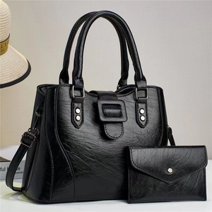 Detail view of black faux leather handbag set with round handles and silver studs