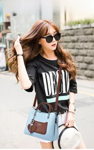 Street style shot of a light blue textured leather handbag with coffee-colored handles