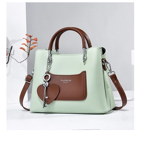 Detail of mint green lychee leather handbag with heart charm and Fashion Queen text