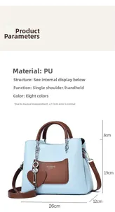 Detailed view of light blue textured handbag with brown straps and heart pendant charm