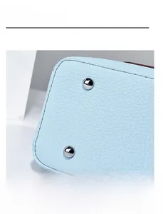 Detail of light blue lychee leather bag bottom with silver protective metal studs