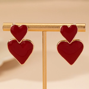Eleganti orecchini a doppio cuore rosso con bordi dorati su un supporto minimalista