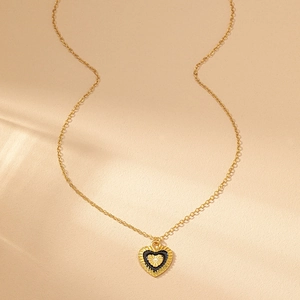 Detail of a vintage golden heart necklace with black enamel border and textured center