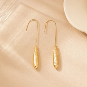Detailed close-up of gold teardrop earrings with hand-hammered texture and curved hooks