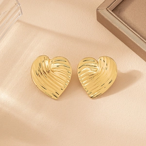 Detail view of heart-shaped gold studs featuring elegant pleated texture and glossy finish