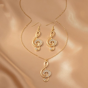 Détail de l'ensemble bijoux note de musique dorée et strass sur satin de champagne