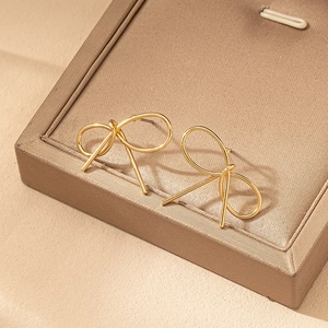 Boucles d'oreilles nœuds dorées minimalistes présentées sur un support en velours