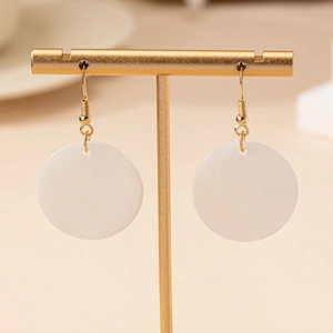 Boucles d'oreilles minimalistes en nacre blanche avec crochets dorés sur présentoir