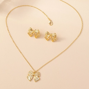 Macro detail of golden bow necklace and earrings set with fine vertical striped texture