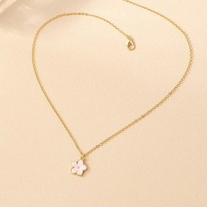 Gros plan du pendentif fleur rose sur chaîne dorée avec détails en émail fin