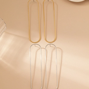 Macro detail of polished gold and silver minimalist geometric oval hoop drop earrings